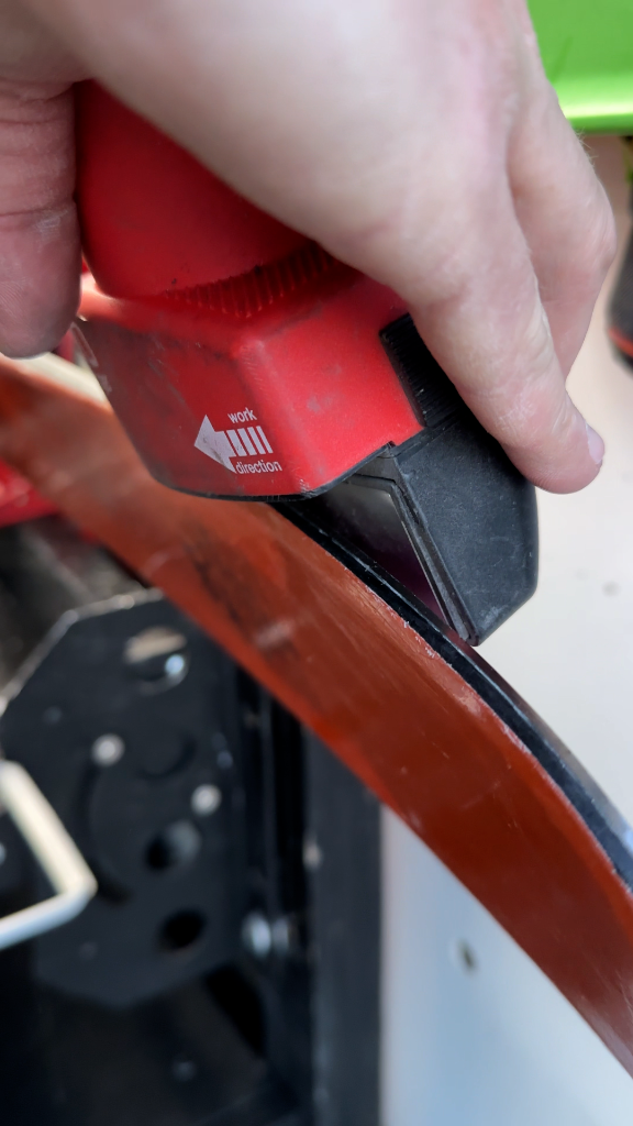 Close-up of professional hand scraping ski edge showing expert precision and attention to detail